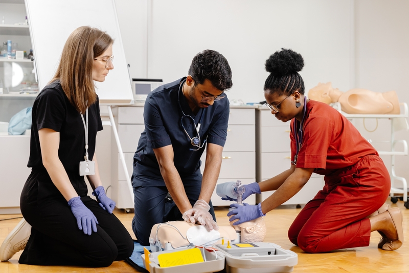 Three medical personnel practice ACLS on a medical mannequin